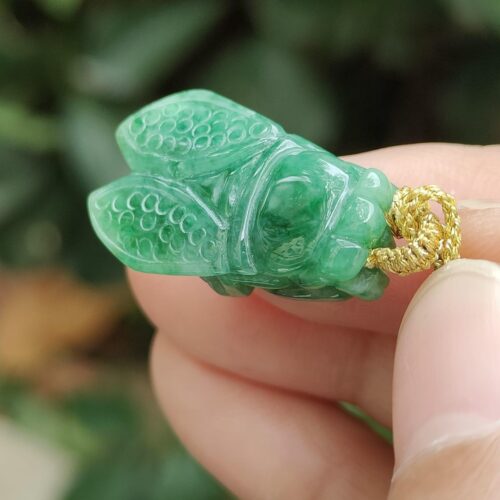 a hand holding a jade insect pendant