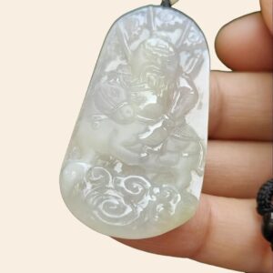 a hand holding a jade pendant