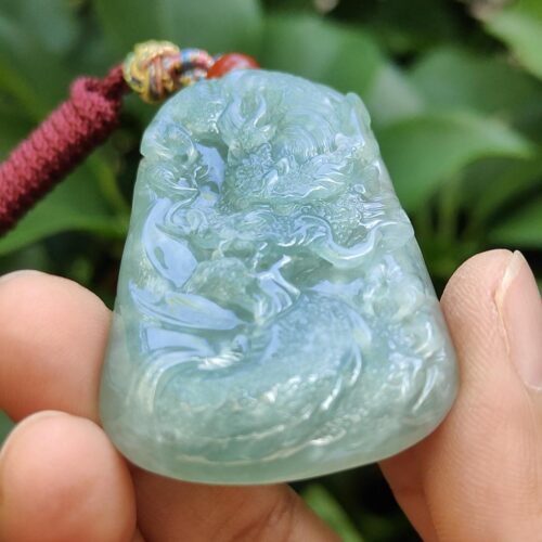 une main tenant un pendentif en jade