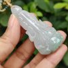 a hand holding a jade pendant