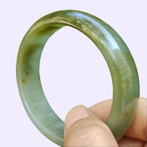 a hand holding a green ring