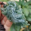a hand holding a jade pendant