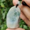 a hand holding a jade pendant