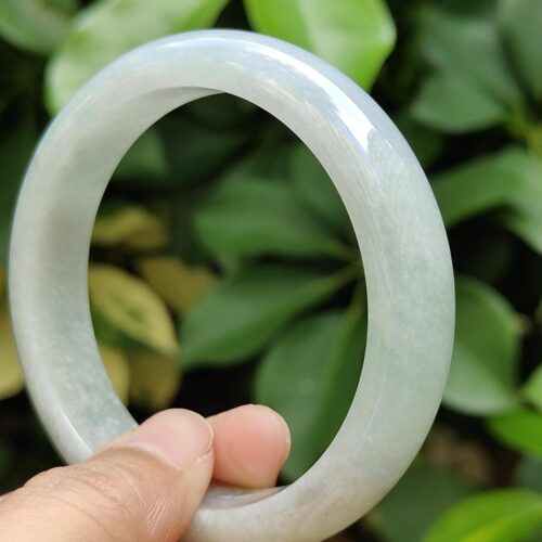 a hand holding a white round bracelet