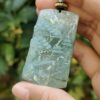 a hand holding a jade pendant