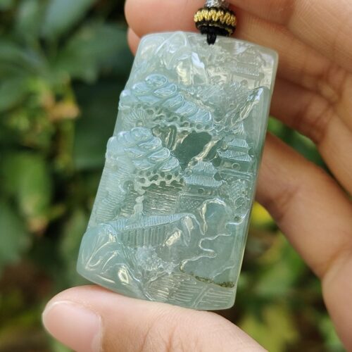 a hand holding a jade pendant