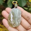 a hand holding a jade pendant