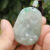 a hand holding a jade pendant
