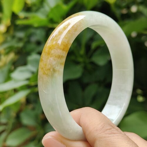a hand holding a white and yellow bracelet