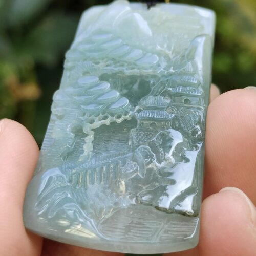 a hand holding a jade pendant