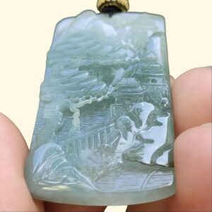 a hand holding a jade pendant