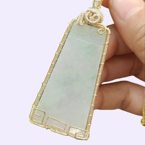 une main tenant un pendentif en jade