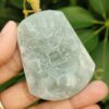 a hand holding a jade pendant
