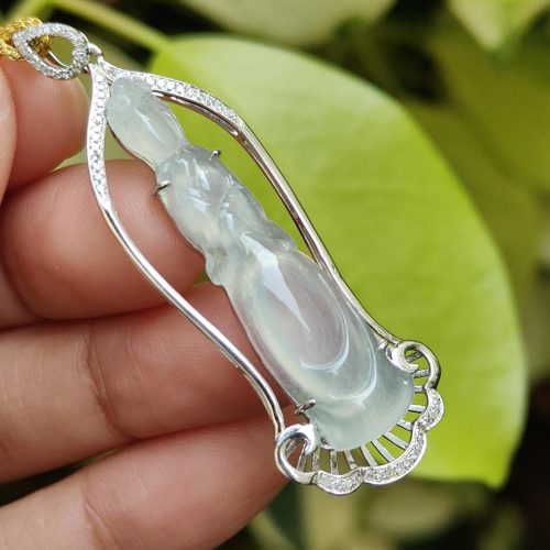 a hand holding a jade pendant