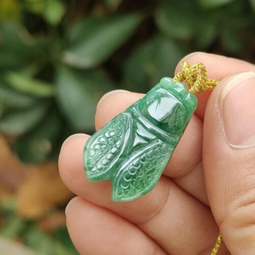 a hand holding a jade pendant