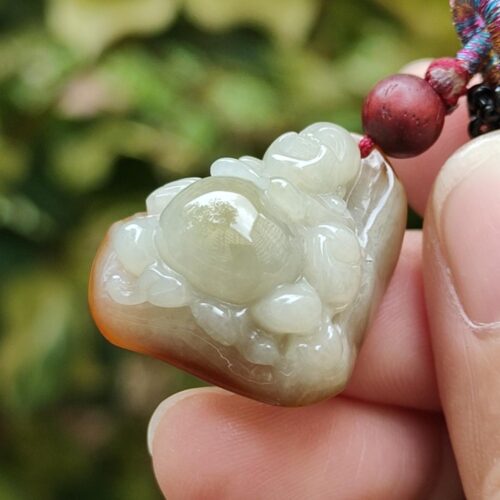 ஜேட் பதக்கத்தை வைத்திருக்கும் ஒரு கை