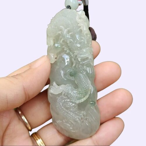 une main tenant un pendentif en jade