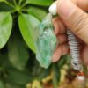 une main tenant un pendentif en jade