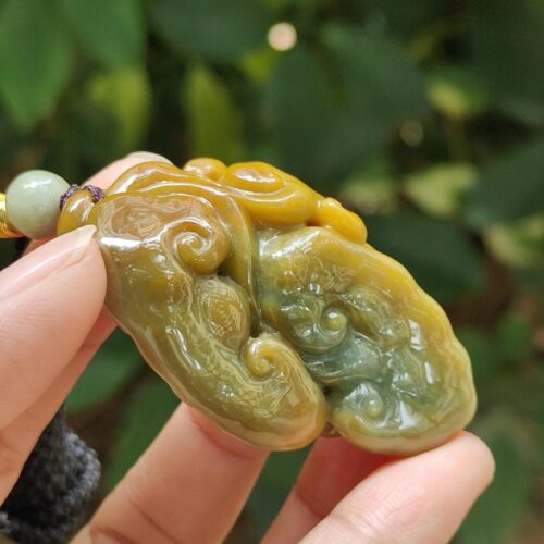 une main tenant un pendentif en jade