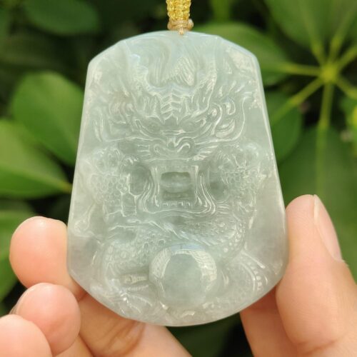 a hand holding a jade pendant