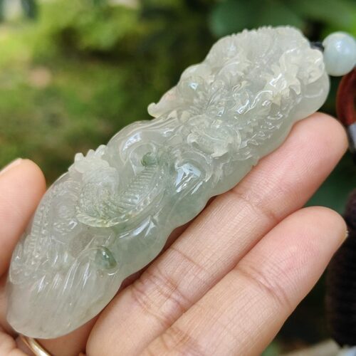 une main tenant un pendentif en jade