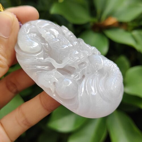 a hand holding a white jade object