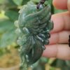 a hand holding a jade pendant