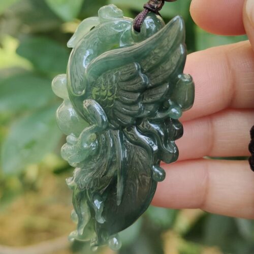 a hand holding a jade pendant