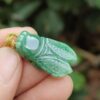 a hand holding a green insect pendant