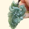 a hand holding a jade pendant