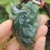 a hand holding a jade pendant