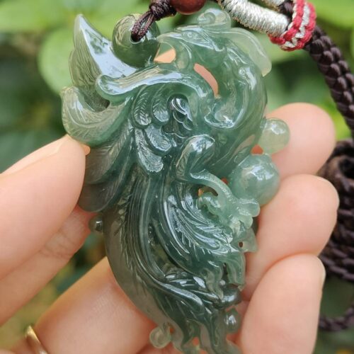 a hand holding a jade pendant