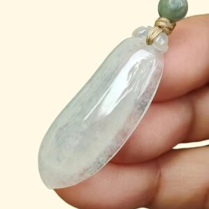 a hand holding a jade pendant