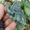 a hand holding a jade pendant