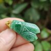 a hand holding a jade insect pendant