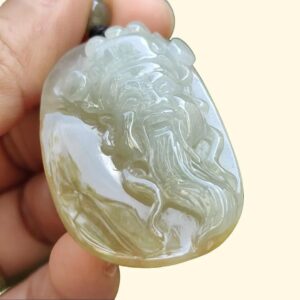 a hand holding a jade pendant