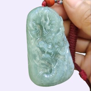 a hand holding a jade pendant