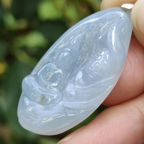 a hand holding a jade pendant