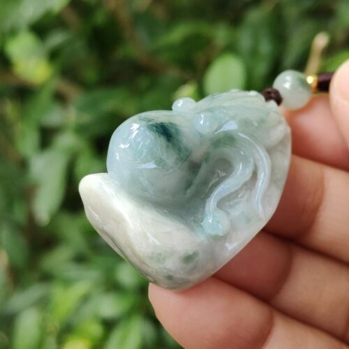 a hand holding a jade pendant