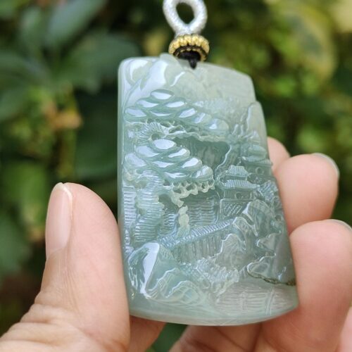 a hand holding a jade pendant