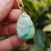 a hand holding a jade pendant