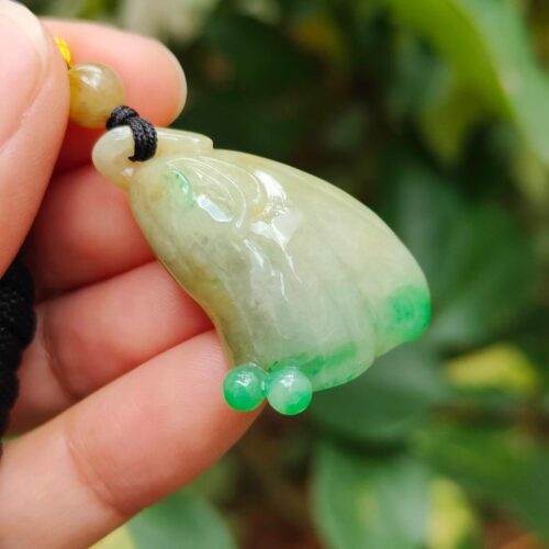 ஜேட் பதக்கத்தை வைத்திருக்கும் ஒரு கை