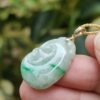 a hand holding a jade pendant