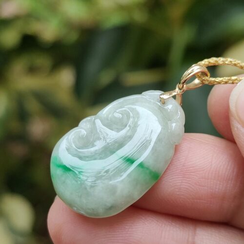 a hand holding a jade pendant