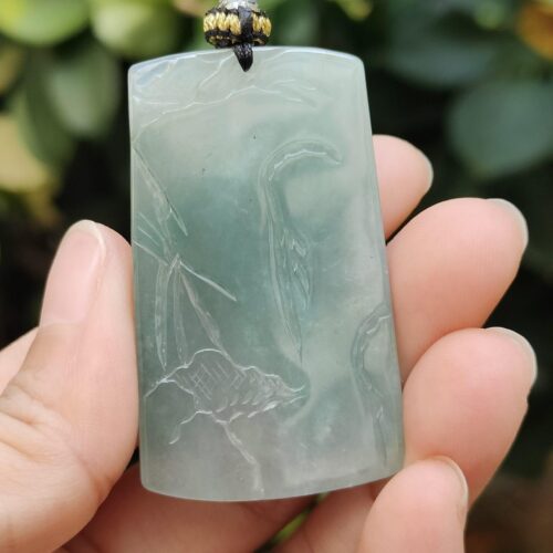 a hand holding a jade pendant