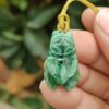 a hand holding a jade pendant