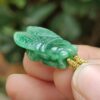 a hand holding a jade bug pendant