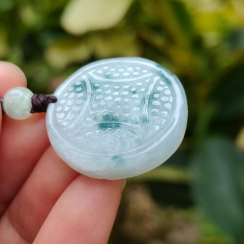 tangan memegang liontin giok