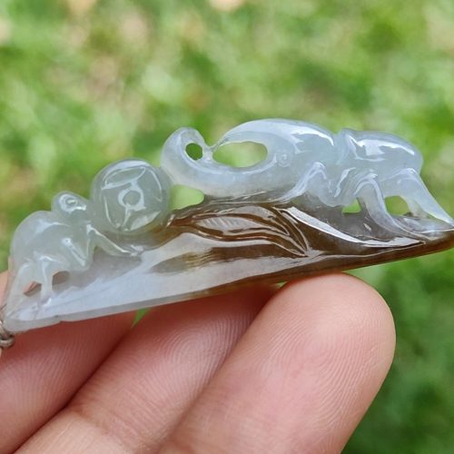 a hand holding a jade pendant