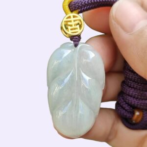 a hand holding a jade pendant